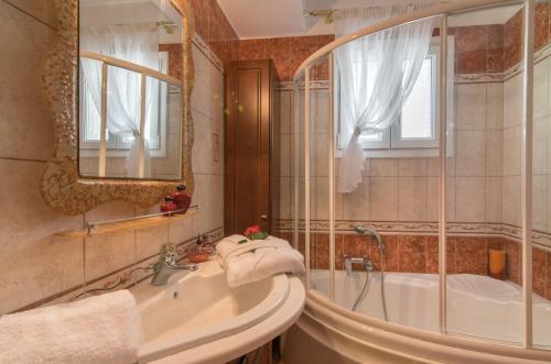 a bathroom with a tub and a sink and a mirror at Fontana Holiday Home in Mouzákion