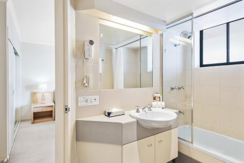a white bathroom with a sink and a shower at Dockside Brisbane in Brisbane