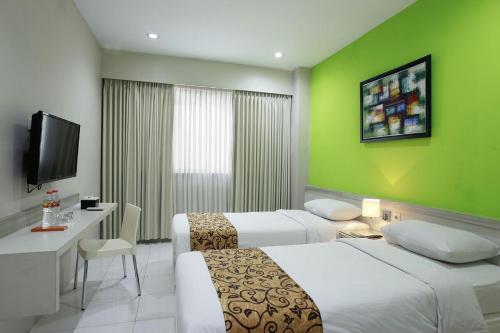 a hotel room with two beds and a television at Rivisha Hotel in Yogyakarta