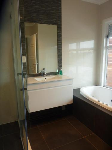 a bathroom with a sink and a tub and a mirror at Lincoln View Holiday House in North Shields