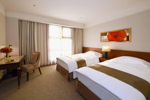 a hotel room with two beds and a desk at Fullon Hotel Taoyuan in Taoyuan