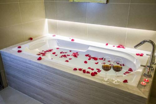a bath tub filled with red roses and wine glasses at GreenTree Inn Jiangsu Taizhou Dongfeng Road Express Hotel in Taizhou
