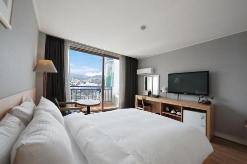 a hotel room with a large bed and a television at Benikea Swiss Rosen Hotel in Gyeongju