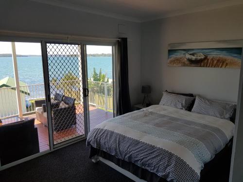 een slaapkamer met een bed en uitzicht op de oceaan bij The Lake Escape in Mannering Park
