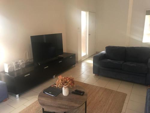 a living room with a couch and a tv at The Clan Terrigal in Terrigal