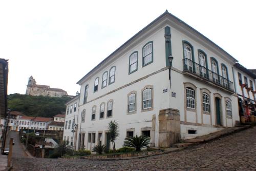 a large white building on a cobblestone street at Hotel Luxor in Ouro Preto