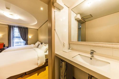 a bathroom with a bed and a sink and a mirror at Incheon Airport Hotel Seattle in Incheon