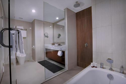 La salle de bains est pourvue d'une douche, d'une baignoire et de toilettes. dans l'établissement The Alana Hotel and Conference Sentul City by ASTON, à Bogor