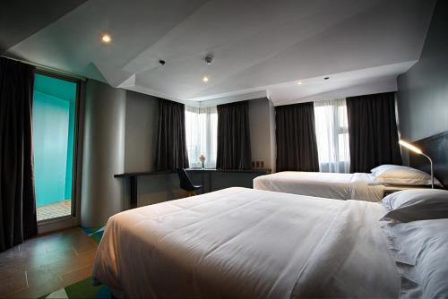 a hotel room with two beds and a desk at G1 Lodge in Baguio