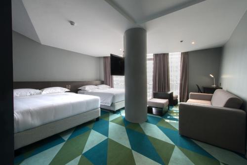 a hotel room with two beds and a couch at G1 Lodge in Baguio