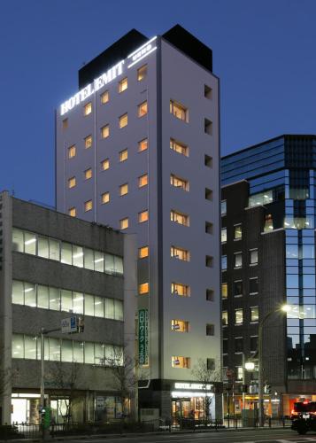 a tall building with lights on in a city at Hotel Emit Ueno in Tokyo