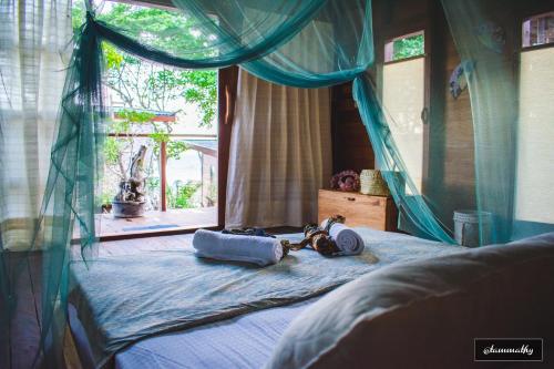 a bedroom with a bed with a blue canopy at Tevana House Reef in Bira