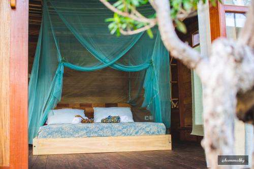 a bed with a blue canopy with two pillows at Tevana House Reef in Bira