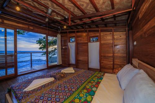 a bedroom with a bed with a view of the ocean at Tevana House Reef in Bira