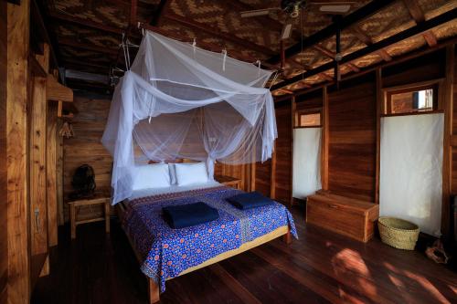 a bedroom with a bed with a mosquito net at Tevana House Reef in Bira
