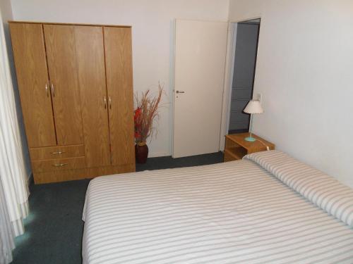 a bedroom with a bed and a dresser and a closet at Complejo Marce in Ostende