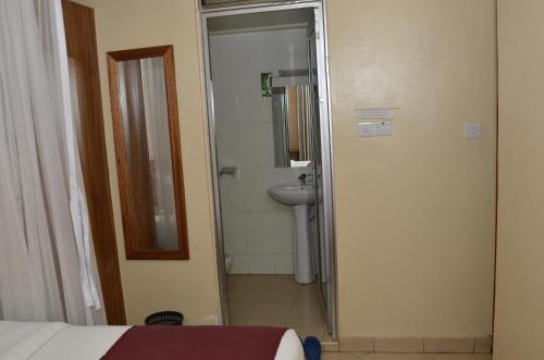 a bathroom with a bed and a sink and a mirror at Decasa Hotel in Nairobi
