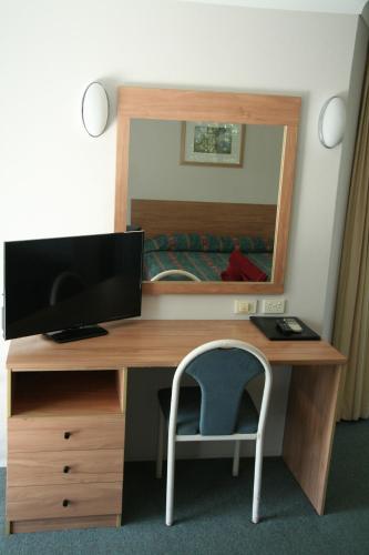 a bedroom with a desk with a computer and a mirror at Colonial Court Motor Inn in Kempsey