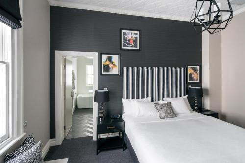 a bedroom with a white bed and a black wall at Mrs Banks Hotel in Sydney