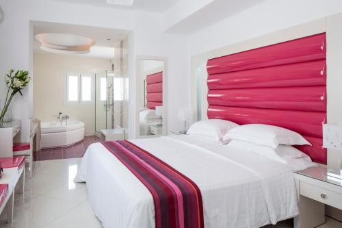 a bedroom with a large bed with a red headboard at Grand Beach Hotel in Mýkonos City