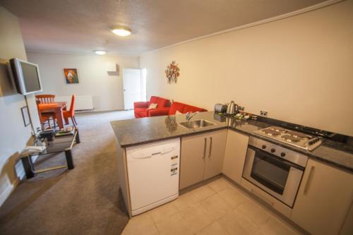 een keuken en een woonkamer met een fornuis en een bank bij City Central Motel Apartments in Christchurch