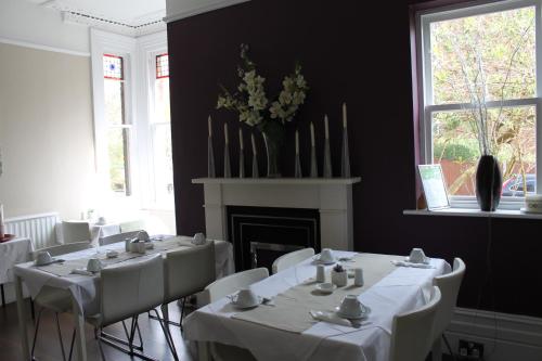 a dining room with white tables and chairs and a fireplace at The Wimbledon Hotel in London