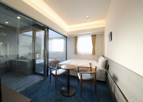 a bedroom with a bed and a table and chairs at Hotel Emit Ueno in Tokyo
