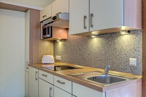 una cocina con armarios blancos y fregadero en Apartments Haus Daniela en Cochem