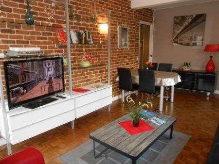 a living room with a tv and a brick wall at Gite Clemenceau in Rouen
