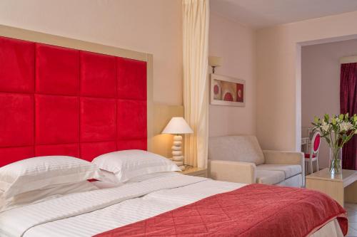a bedroom with a red headboard and a bed at Grand Beach Hotel in Mýkonos City