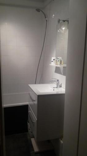 une salle de bain blanche avec un lavabo et un miroir dans l'établissement Le BETHENCOURT, à Dieppe