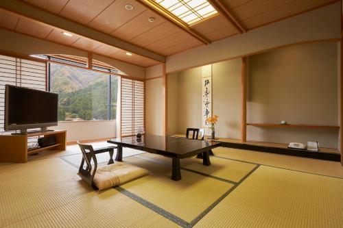 ein Wohnzimmer mit einem Tisch und einem TV in der Unterkunft Kinugawa Onsen Sanraku in Nikko
