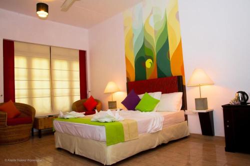 a bedroom with a bed with a colorful painting on the wall at The Kent in Tissamaharama