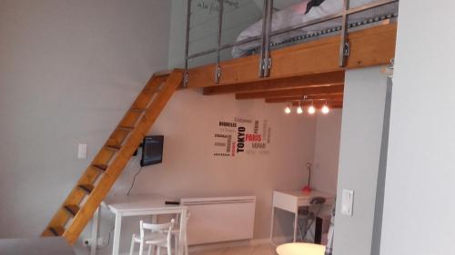 a room with a bunk bed with a desk and a ladder at Studio meublé in Lumes