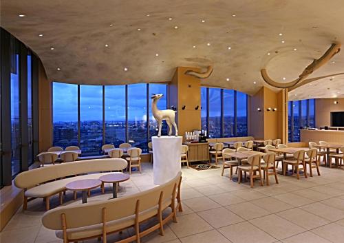 a restaurant with tables and chairs and a dinosaur on the ceiling at KOKO HOTEL Kanazawa Station - formerly Hotel Wing International Premium Kanazawa Ekimae in Kanazawa