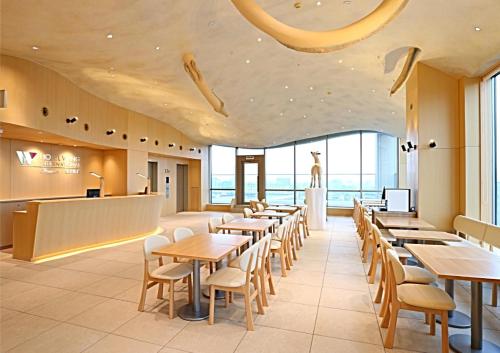 a dining room with tables and chairs and windows at KOKO HOTEL Kanazawa Station in Kanazawa