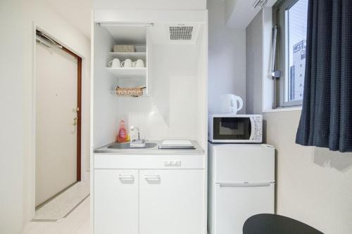 a small kitchen with a white refrigerator and a microwave at NTH Namba - Whole floor 3 flats - Self Check-In Only in Osaka