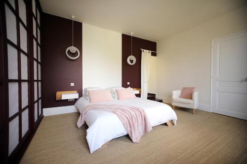 a bedroom with a large white bed and a chair at Les Rêves de Flamboin in Gouaix