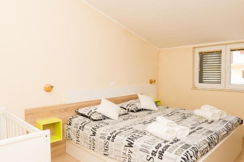 a bedroom with a bed with white sheets and towels at Apartments Sky in Šibenik