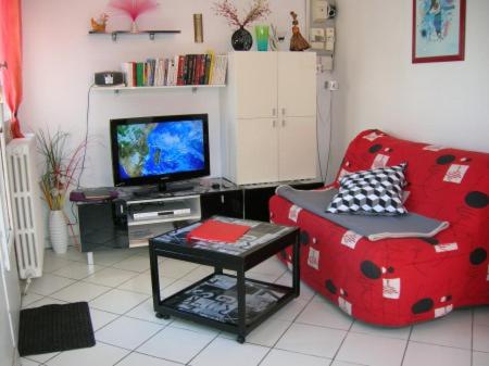 un salon avec une chaise rouge et une télévision dans l'établissement Gite B, à Sotteville-lès-Rouen