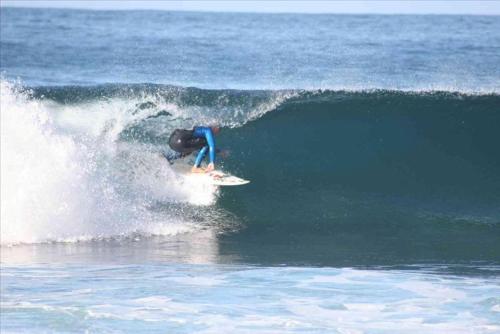 a person riding a wave on a surfboard in the ocean at Hotel Villaggio Ristorante Pizzeria Museo TANIT in Carbonia