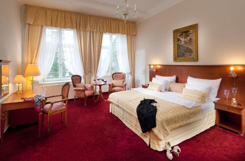 a bedroom with a bed and a desk and chairs at Imperial Spa & Kurhotel in Františkovy Lázně
