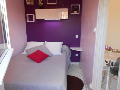 um pequeno quarto com uma cama com uma almofada vermelha em Gite C em Sotteville-lès-Rouen