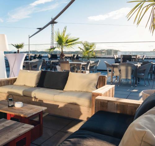 a rooftop patio with couches and tables and chairs at Das Alfred in Sankt Pölten