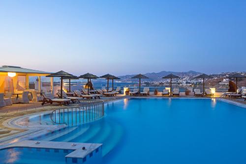 a large swimming pool with chairs and umbrellas at Grand Beach Hotel in Mýkonos City