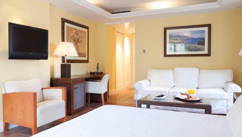 a living room with white furniture and a flat screen tv at Hotel MR Les Rotes in Denia
