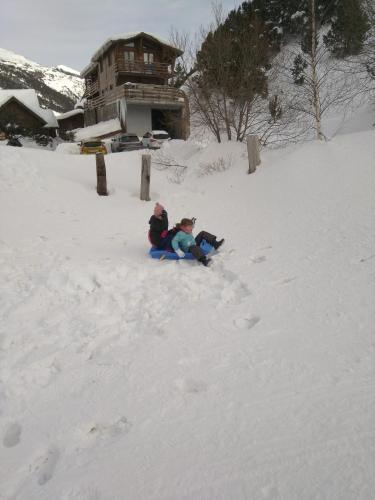 two people sitting in the snow in front of a house at Kione DeuSol in Incles