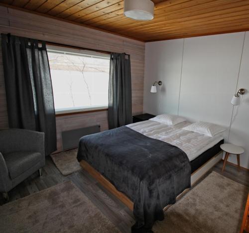 Un dormitorio con una cama y una ventana y una silla. en Villa Kinos, en Utsjoki