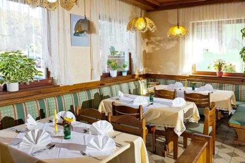 a restaurant with white tables and chairs and windows at Gasthof "zur Bahn" in Lassnitzhöhe