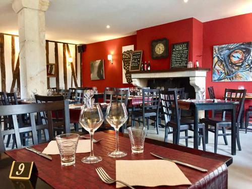 un restaurante con una mesa con copas de vino. en Hôtel Saint Laurans, en Aurignac